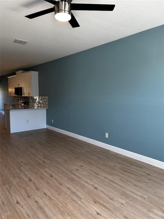 unfurnished living room with ceiling fan, a textured ceiling, and light hardwood / wood-style floors