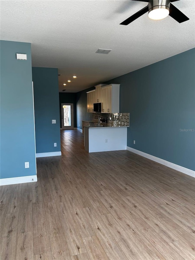 unfurnished living room featuring ceiling fan, light hardwood / wood-style floors, and a textured ceiling