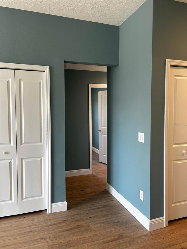 unfurnished bedroom with hardwood / wood-style flooring, a closet, and a textured ceiling