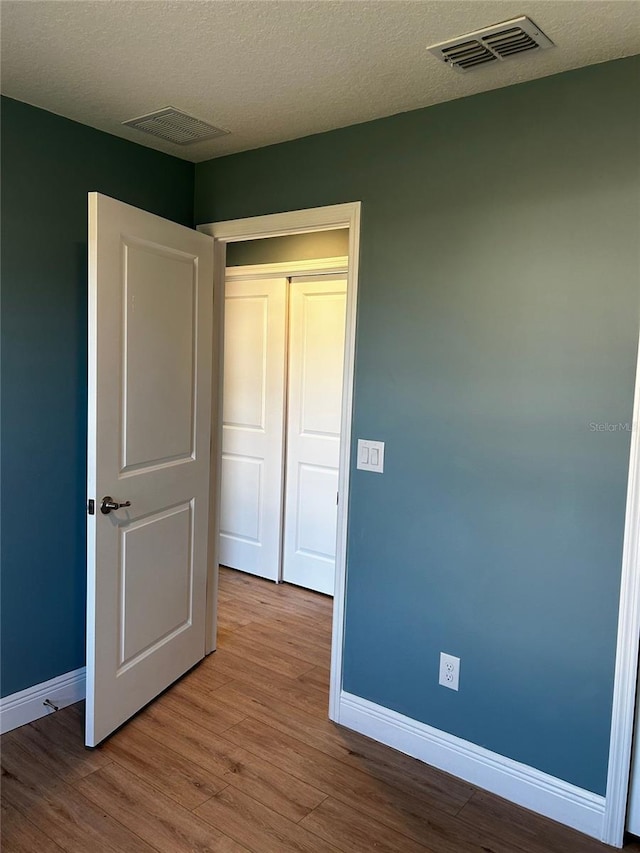 unfurnished bedroom with a textured ceiling and light hardwood / wood-style flooring