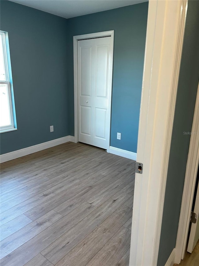 unfurnished bedroom featuring a closet and light wood-type flooring