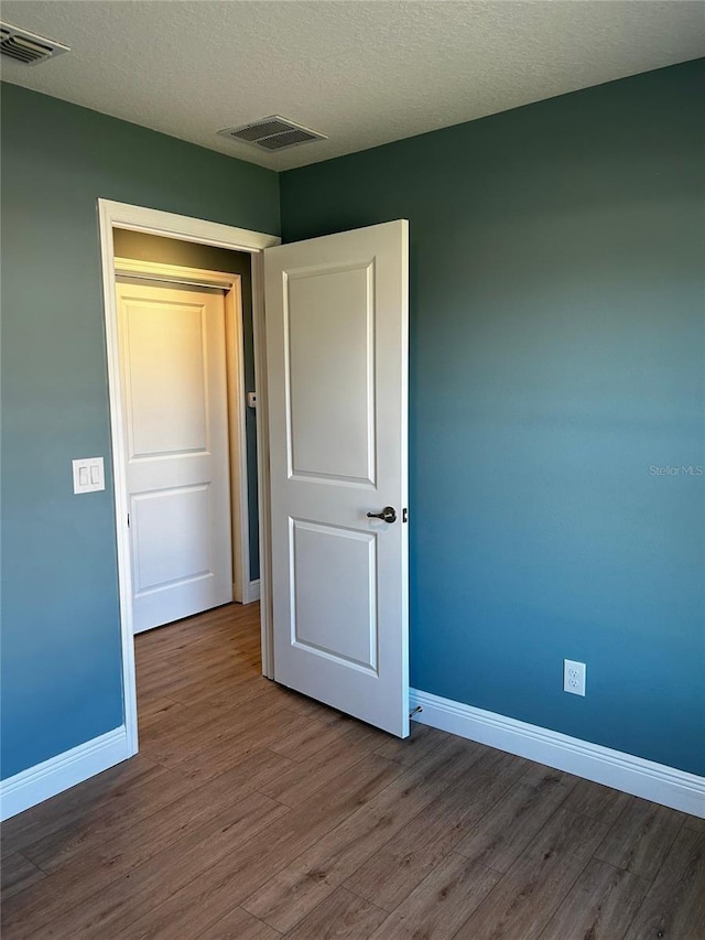 spare room with hardwood / wood-style floors and a textured ceiling