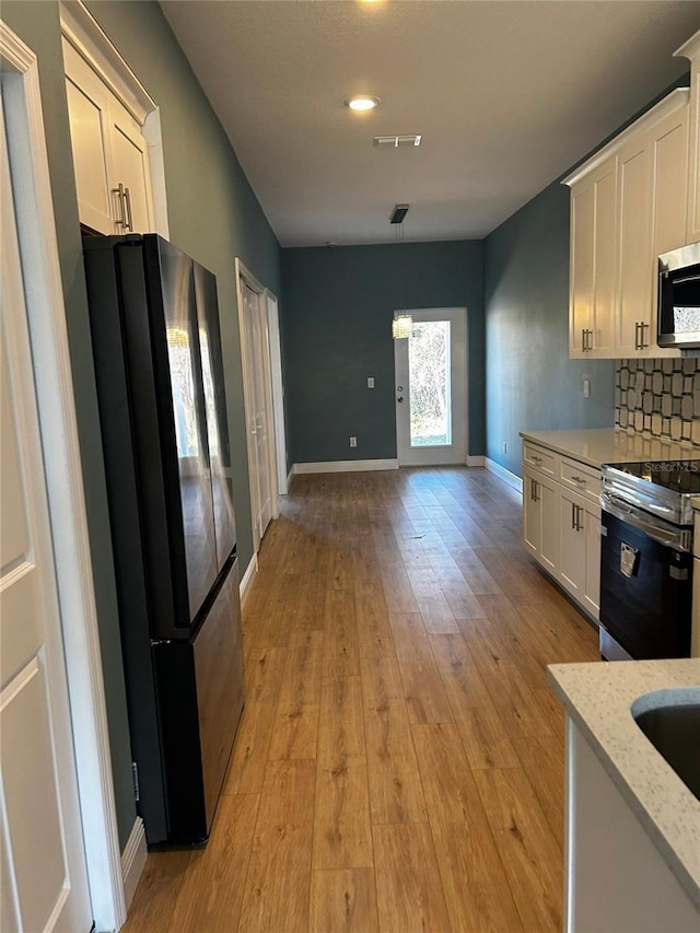 kitchen featuring pendant lighting, decorative backsplash, stainless steel appliances, and white cabinets