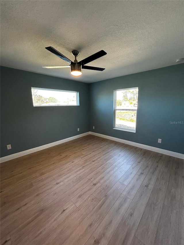 empty room with ceiling fan, light hardwood / wood-style floors, and a textured ceiling