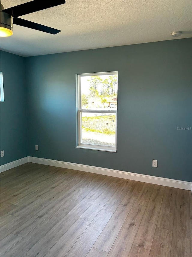 spare room featuring ceiling fan, light hardwood / wood-style floors, and a textured ceiling