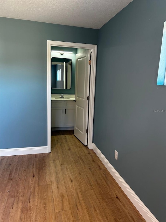 empty room featuring sink, a textured ceiling, and light wood-type flooring