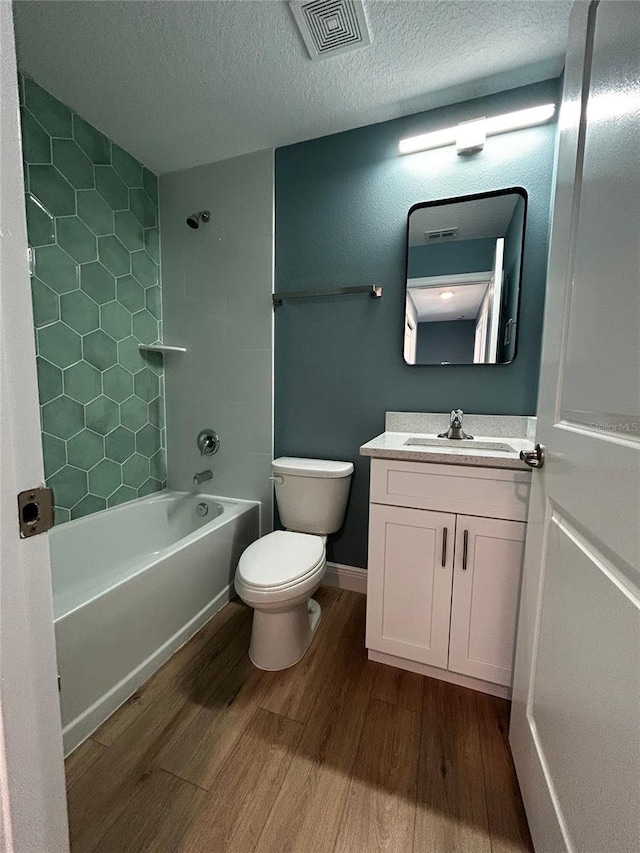 full bathroom with tub / shower combination, hardwood / wood-style floors, vanity, a textured ceiling, and toilet