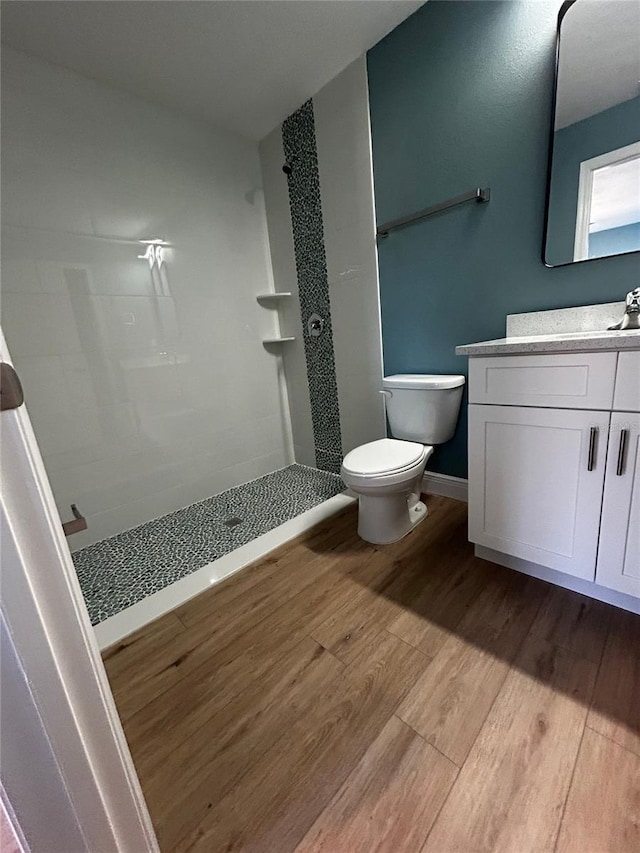 bathroom with vanity, tiled shower, hardwood / wood-style floors, and toilet