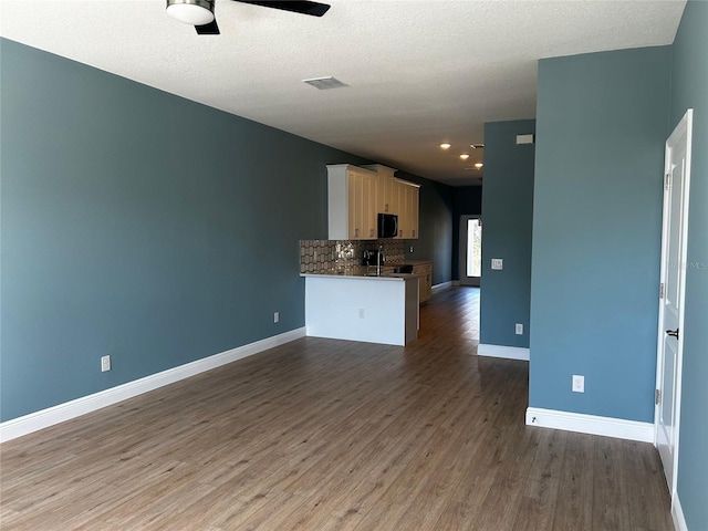 kitchen featuring backsplash, ceiling fan, kitchen peninsula, dark wood-type flooring, and a textured ceiling