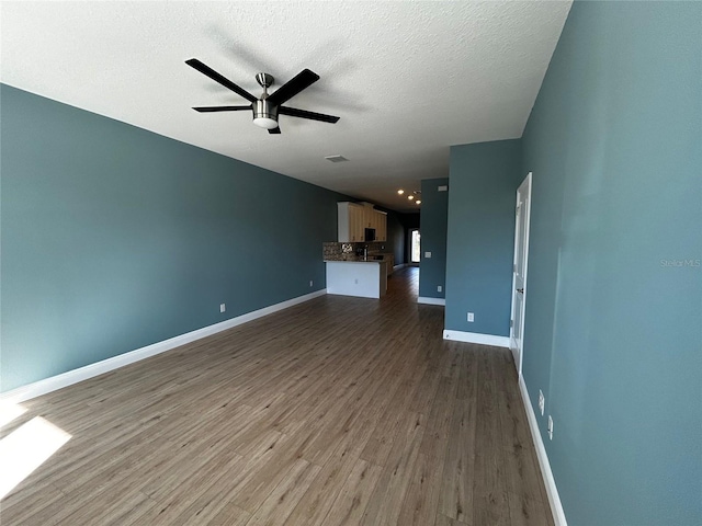 unfurnished living room featuring dark hardwood / wood-style flooring, ceiling fan, and a textured ceiling