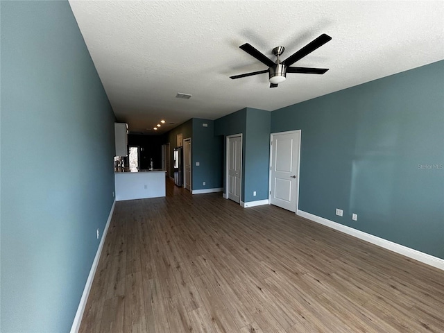 unfurnished living room with wood-type flooring, ceiling fan, and a textured ceiling