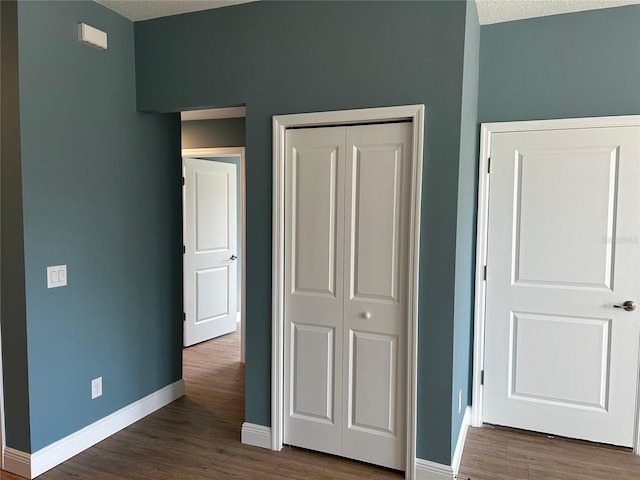 unfurnished bedroom with dark wood-type flooring, a closet, and a textured ceiling