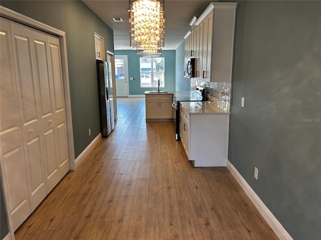 kitchen featuring sink, white cabinetry, electric range, stainless steel refrigerator with ice dispenser, and light wood-type flooring