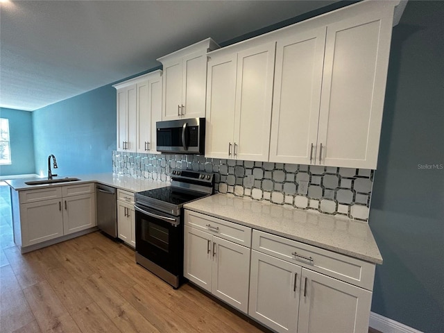 kitchen featuring stainless steel appliances, white cabinetry, sink, and light hardwood / wood-style flooring