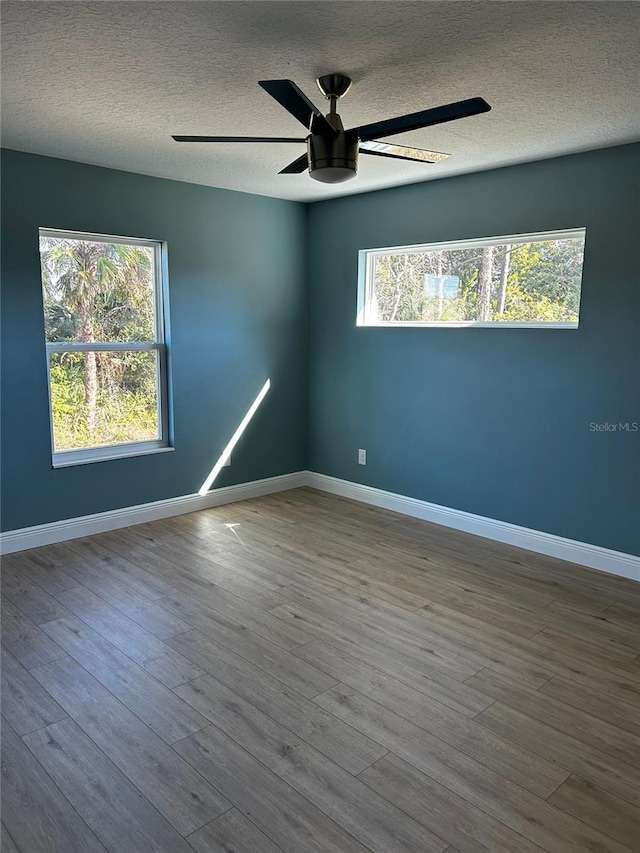 spare room with wood-type flooring, a wealth of natural light, ceiling fan, and a textured ceiling