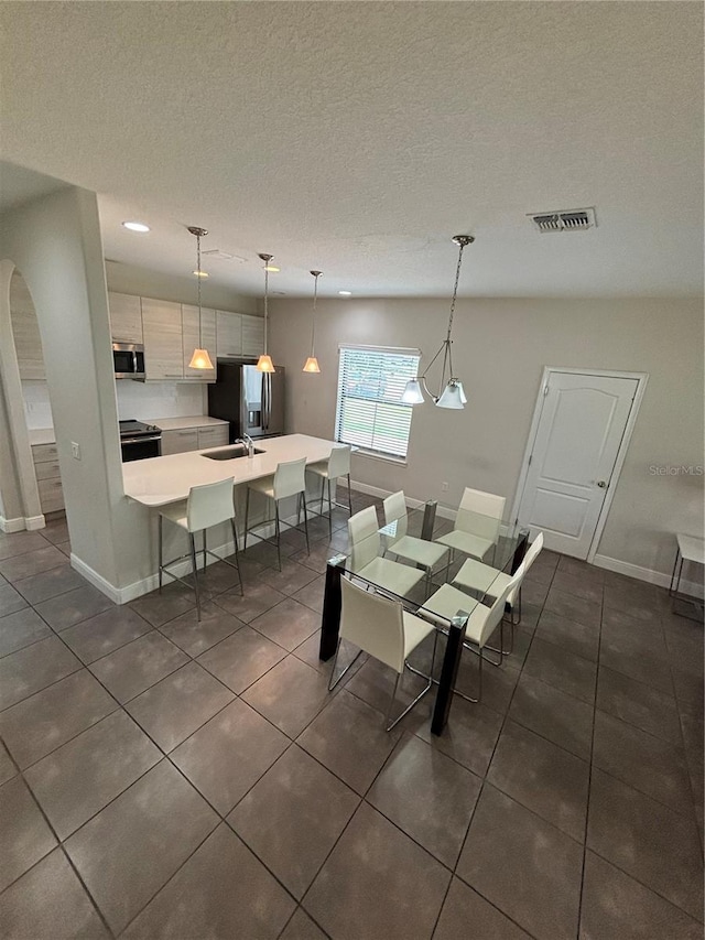 tiled dining space with sink and a textured ceiling