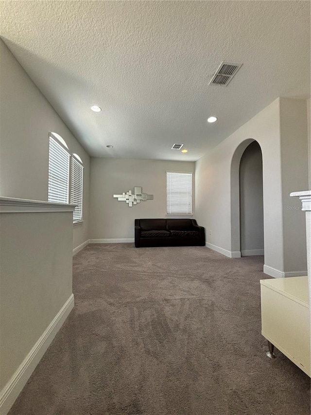 hallway with carpet floors and a textured ceiling