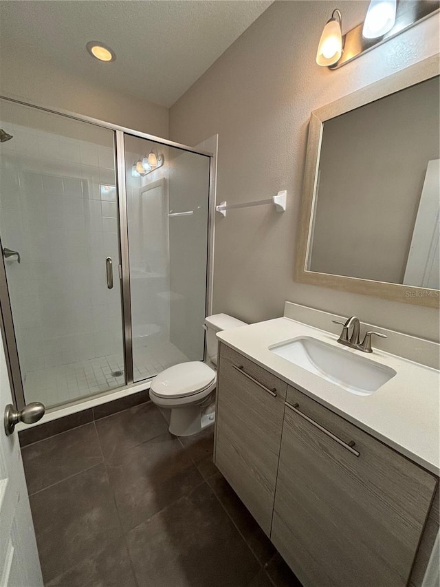 bathroom featuring a shower with door, vanity, and toilet