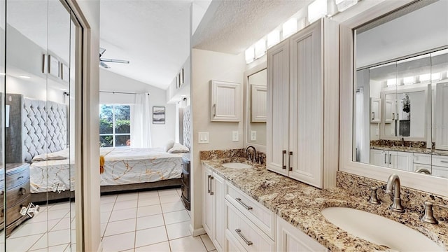 bathroom featuring lofted ceiling, ceiling fan, tile patterned flooring, vanity, and a textured ceiling