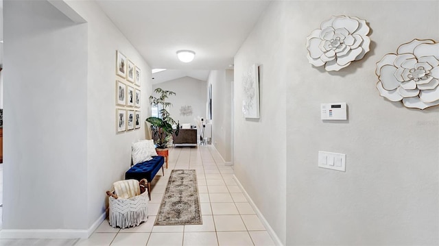 hall featuring light tile patterned flooring and lofted ceiling