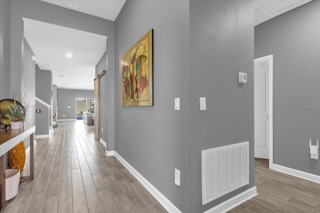 hallway featuring light hardwood / wood-style floors and a barn door