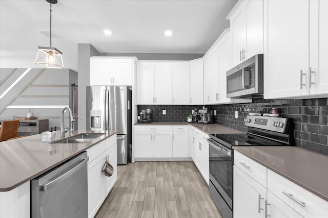 kitchen with white cabinetry, appliances with stainless steel finishes, and decorative light fixtures