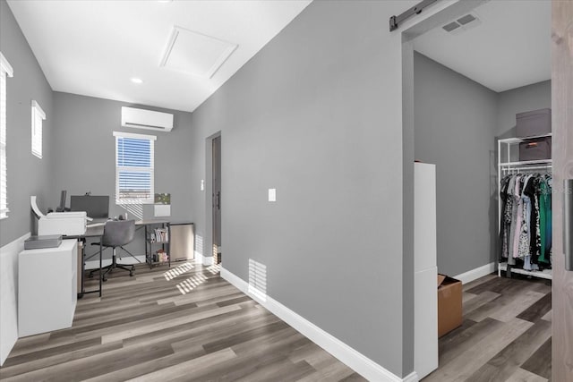 office with a wall mounted air conditioner, a barn door, and light wood-type flooring