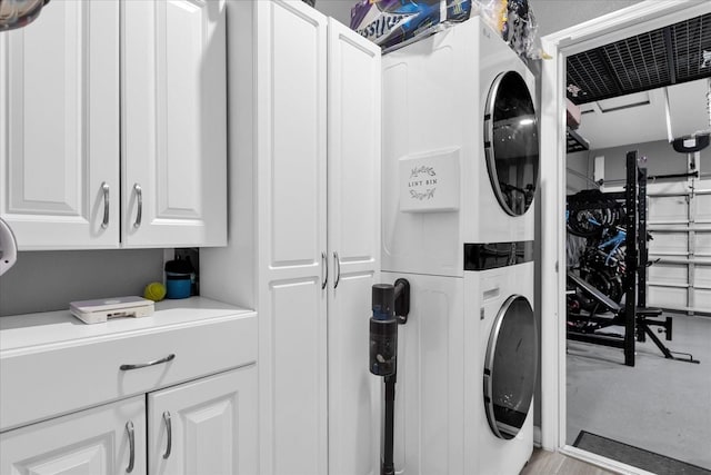 laundry area with cabinets and stacked washer and dryer