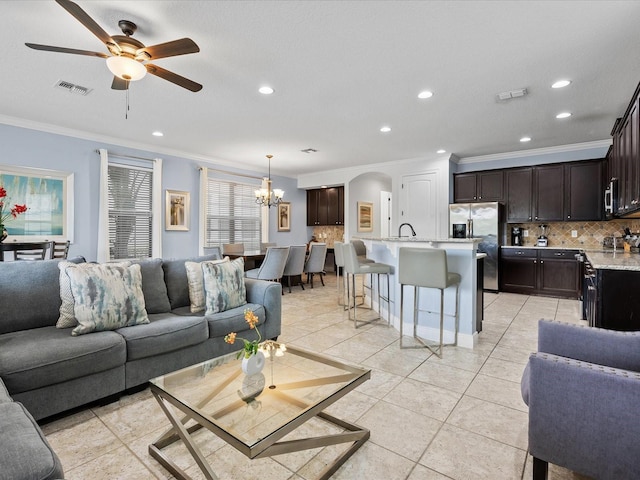 living room with light tile patterned flooring, ornamental molding, sink, and ceiling fan with notable chandelier