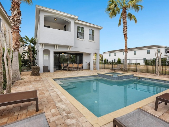 rear view of property with a patio area and a pool with hot tub