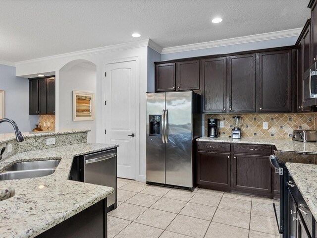 kitchen with dark brown cabinetry, appliances with stainless steel finishes, light stone countertops, and sink