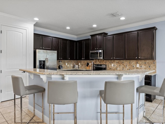 kitchen with stainless steel appliances, light stone countertops, backsplash, and a kitchen breakfast bar