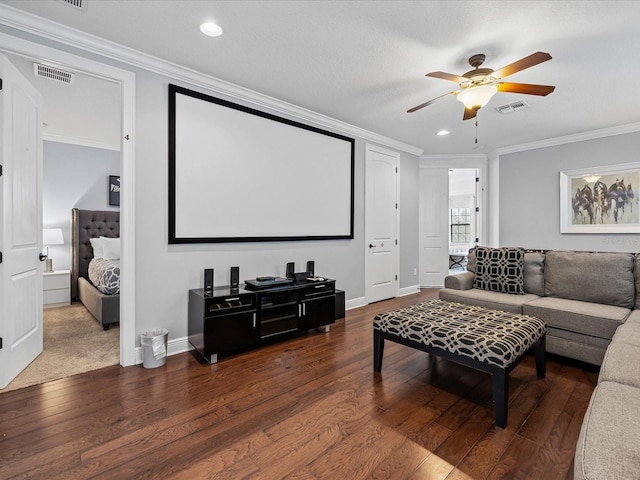 cinema room with dark wood-type flooring, ceiling fan, and ornamental molding