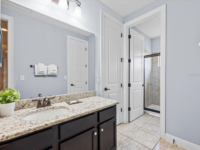 bathroom with vanity, tile patterned flooring, and a shower with door