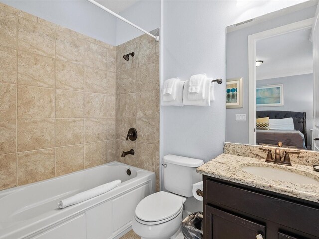 full bathroom with tiled shower / bath combo, vanity, and toilet