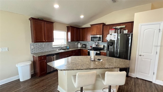 kitchen featuring sink, vaulted ceiling, stainless steel appliances, and light stone countertops