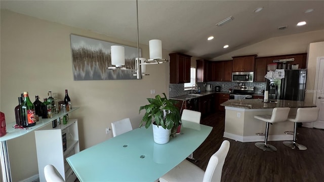 dining space featuring lofted ceiling, sink, and dark wood-type flooring