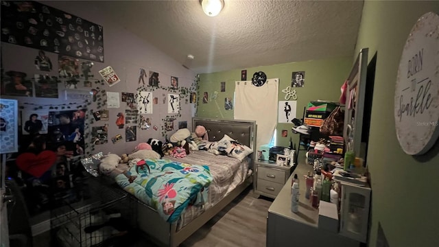 bedroom with vaulted ceiling, light wood-type flooring, and a textured ceiling