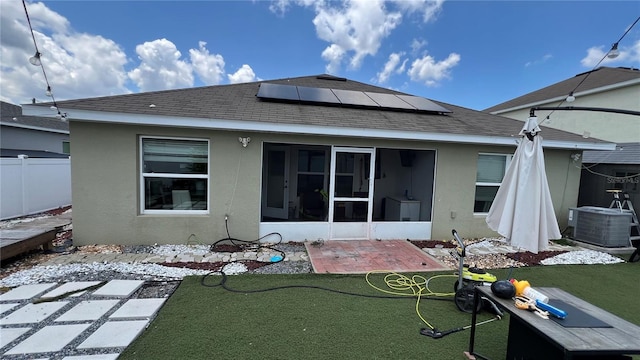 rear view of property with solar panels, a lawn, cooling unit, a sunroom, and a patio area