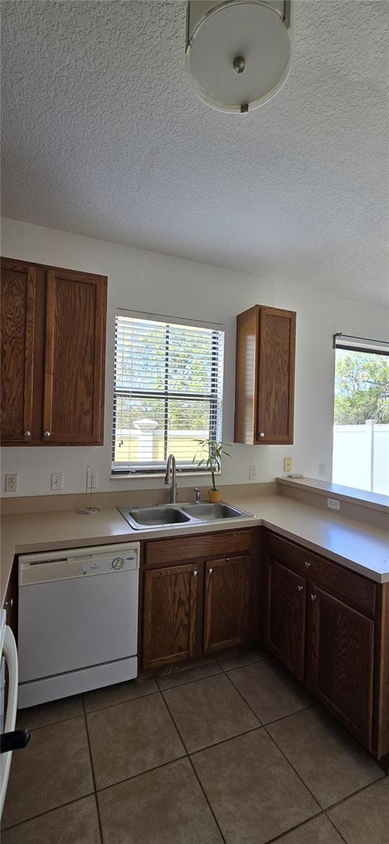 kitchen with white dishwasher, sink, plenty of natural light, and a textured ceiling