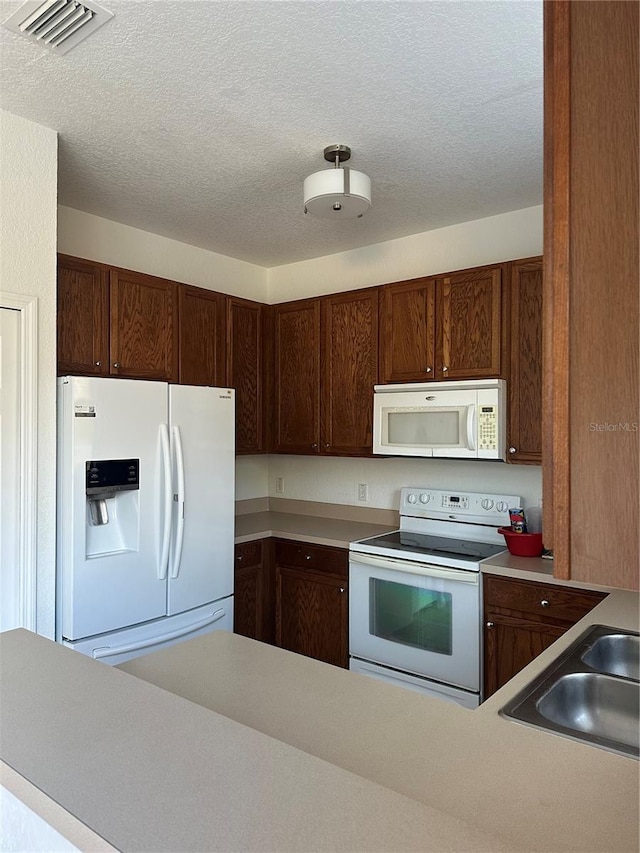 kitchen with sink, a textured ceiling, and white appliances