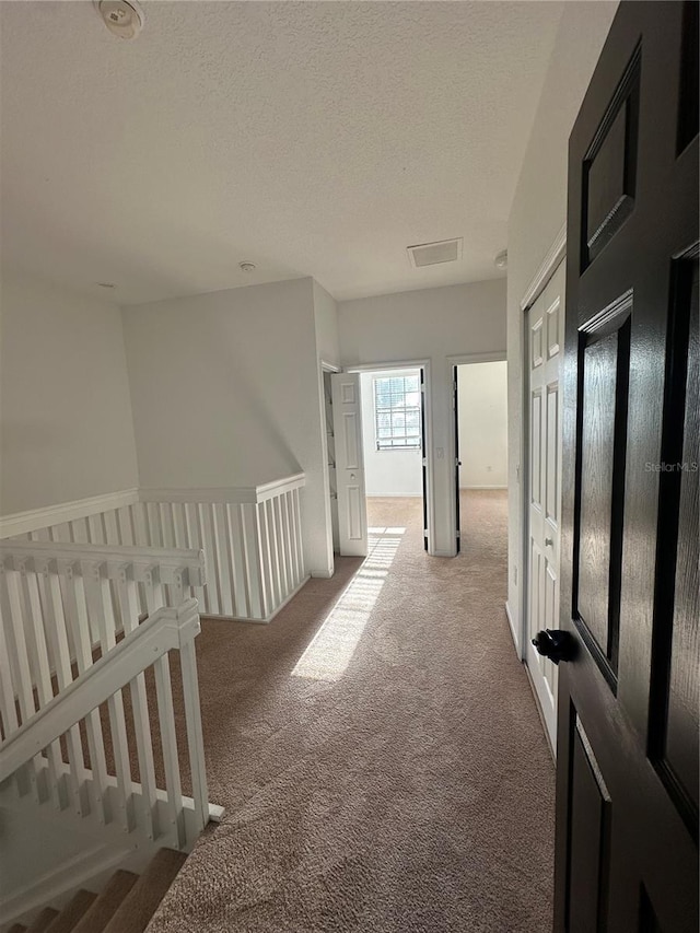 hallway with carpet and a textured ceiling