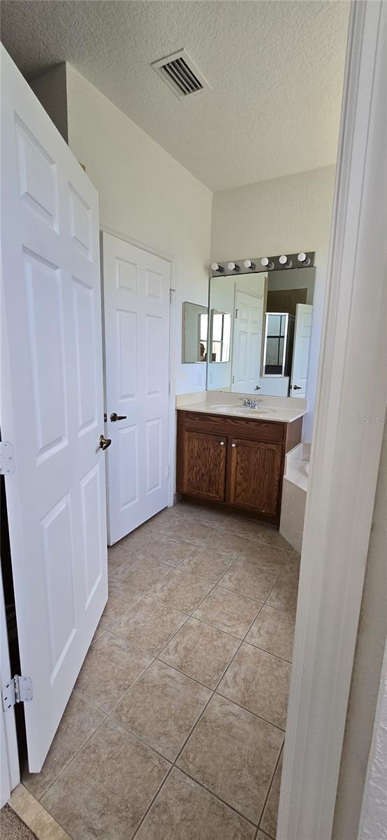 bathroom with tile patterned flooring, vanity, and a textured ceiling