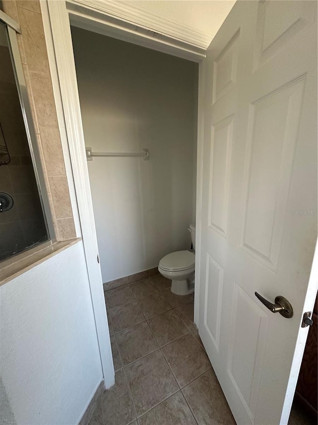 bathroom with a shower, tile patterned floors, and toilet