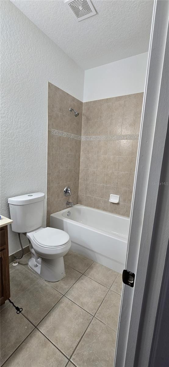 full bathroom featuring toilet, tiled shower / bath, a textured ceiling, vanity, and tile patterned flooring