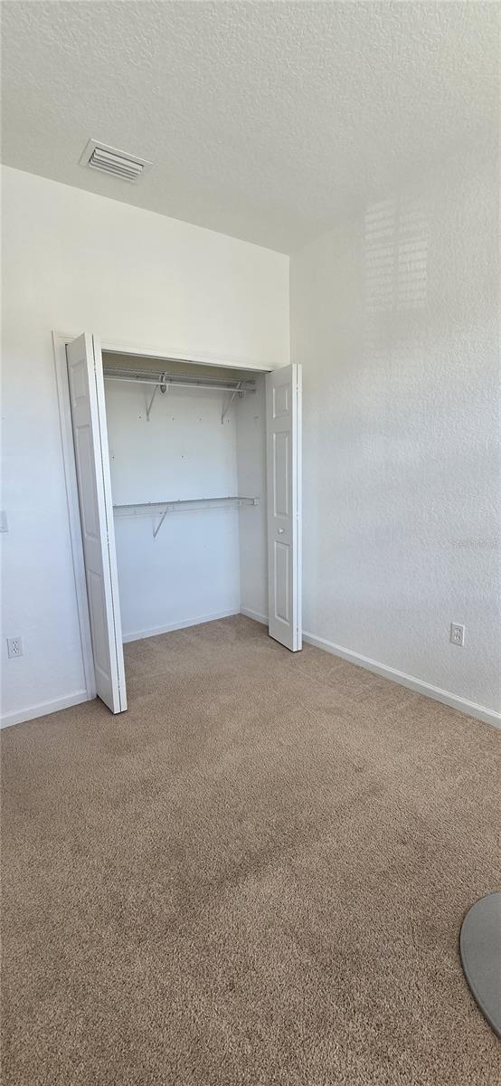 unfurnished bedroom with carpet floors, a closet, and a textured ceiling