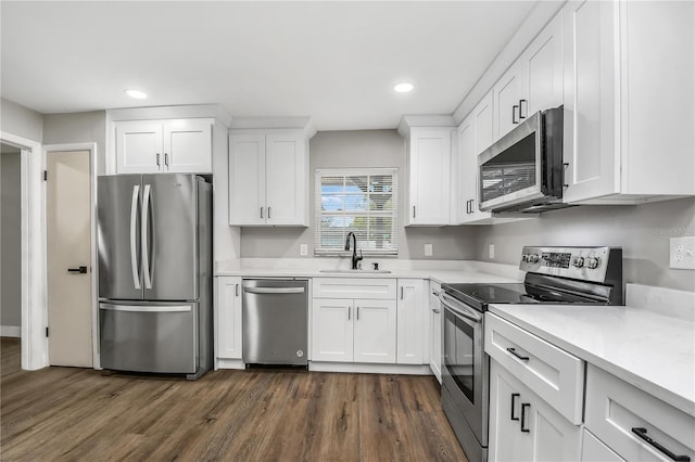 kitchen with appliances with stainless steel finishes, sink, white cabinets, and dark hardwood / wood-style flooring