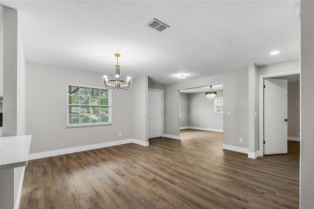 interior space with dark hardwood / wood-style floors, a textured ceiling, and a notable chandelier