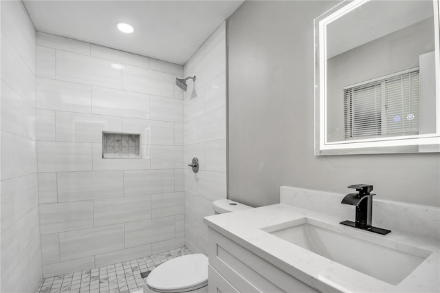 bathroom with vanity, tiled shower, and toilet