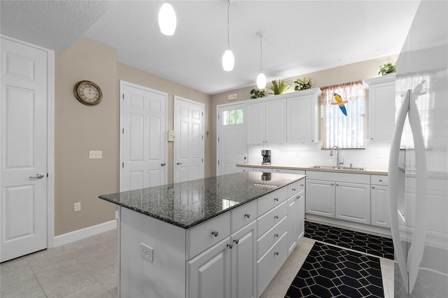 kitchen featuring sink, white refrigerator, white cabinets, and a kitchen island